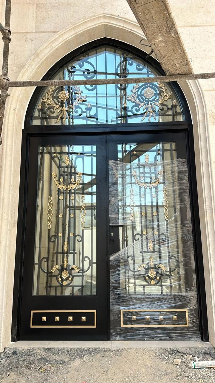 Arched wrought-iron entrance door with gold scrollwork and grille transom